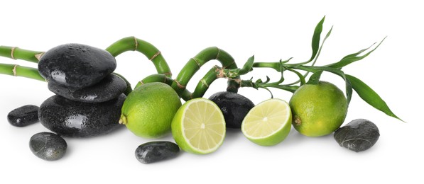 Photo of Spa composition with limes, massage stones and bamboo stems isolated on white