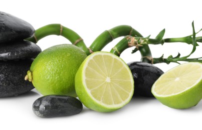 Photo of Spa composition with limes, massage stones and bamboo stems isolated on white