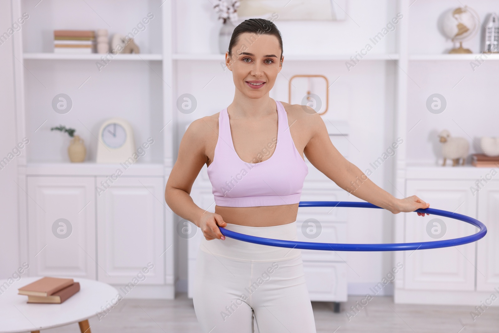 Photo of Smiling woman training with hula hoop at home