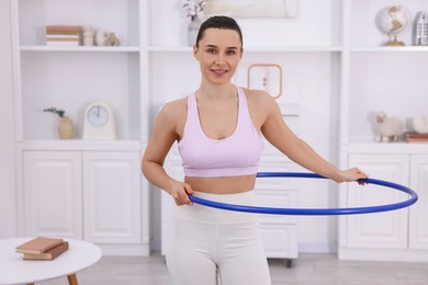 Photo of Smiling woman training with hula hoop at home