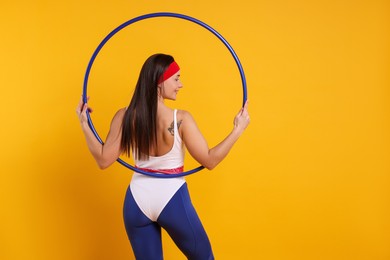 Photo of Smiling woman with hula hoop on orange background, back view