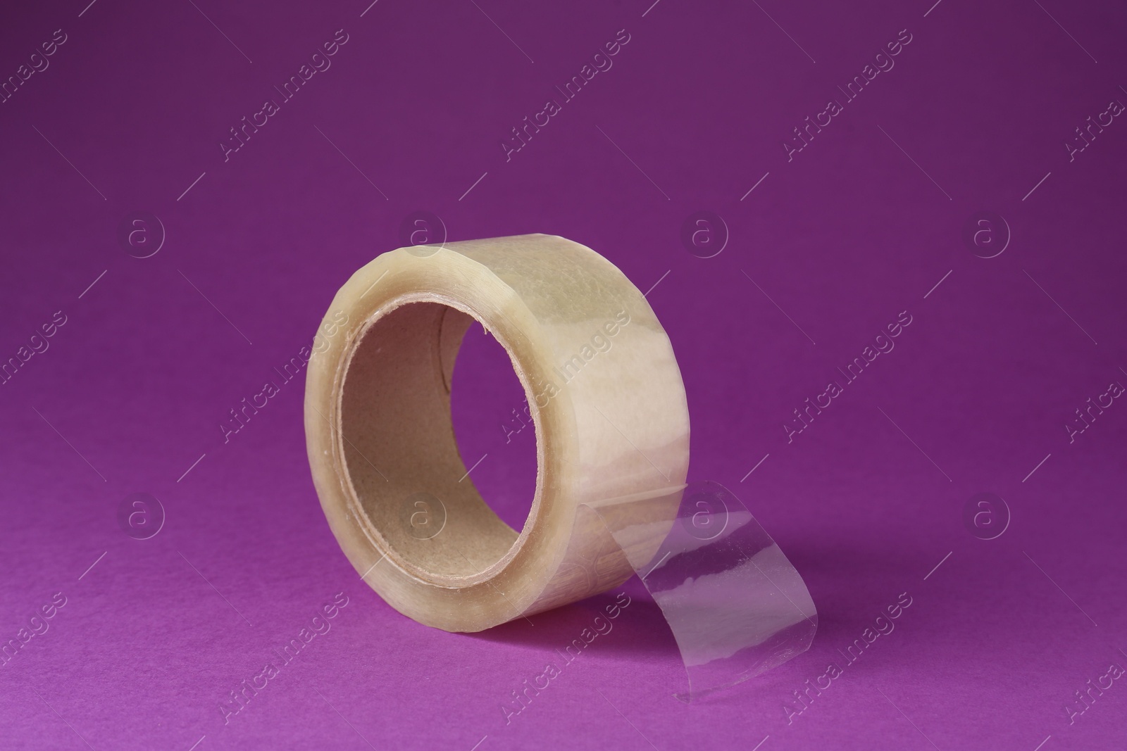 Photo of Roll of adhesive tape on violet background