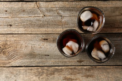 Photo of Refreshing cola with ice cubes in glasses on wooden table, flat lay. Space for text