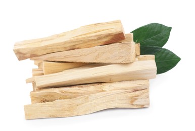 Pile of palo santo sticks and green leaves on white background