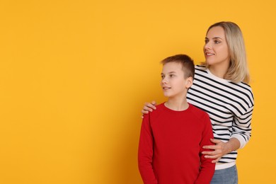 Photo of Happy mother and son on orange background. Space for text