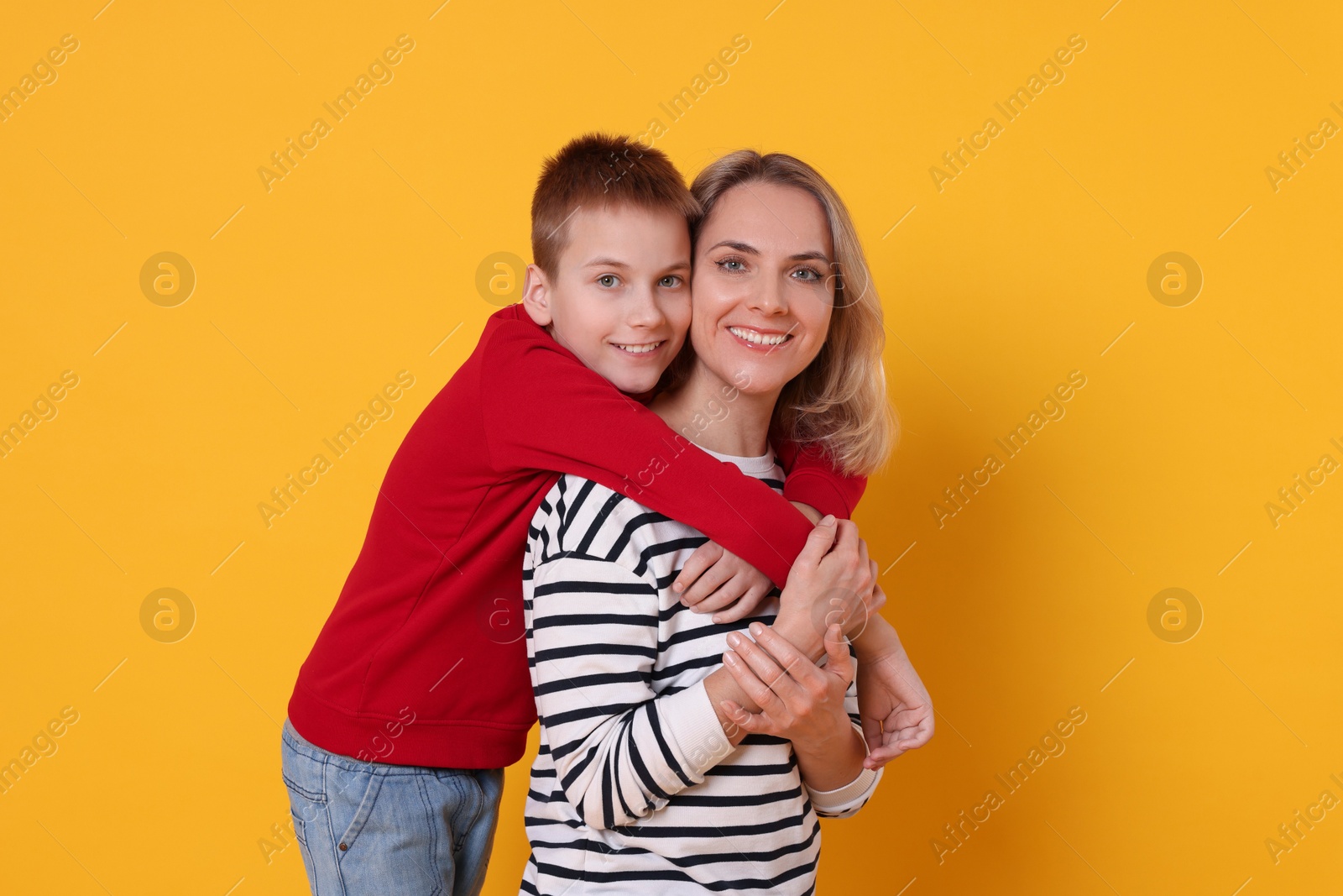 Photo of Mother and son hugging on orange background