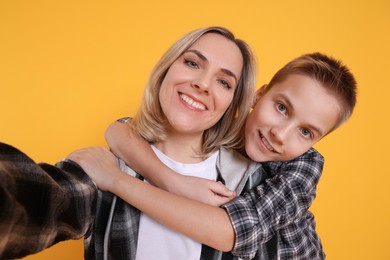 Photo of Happy mother and son taking selfie on orange background