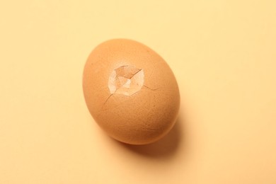 One egg with cracked shell on beige background