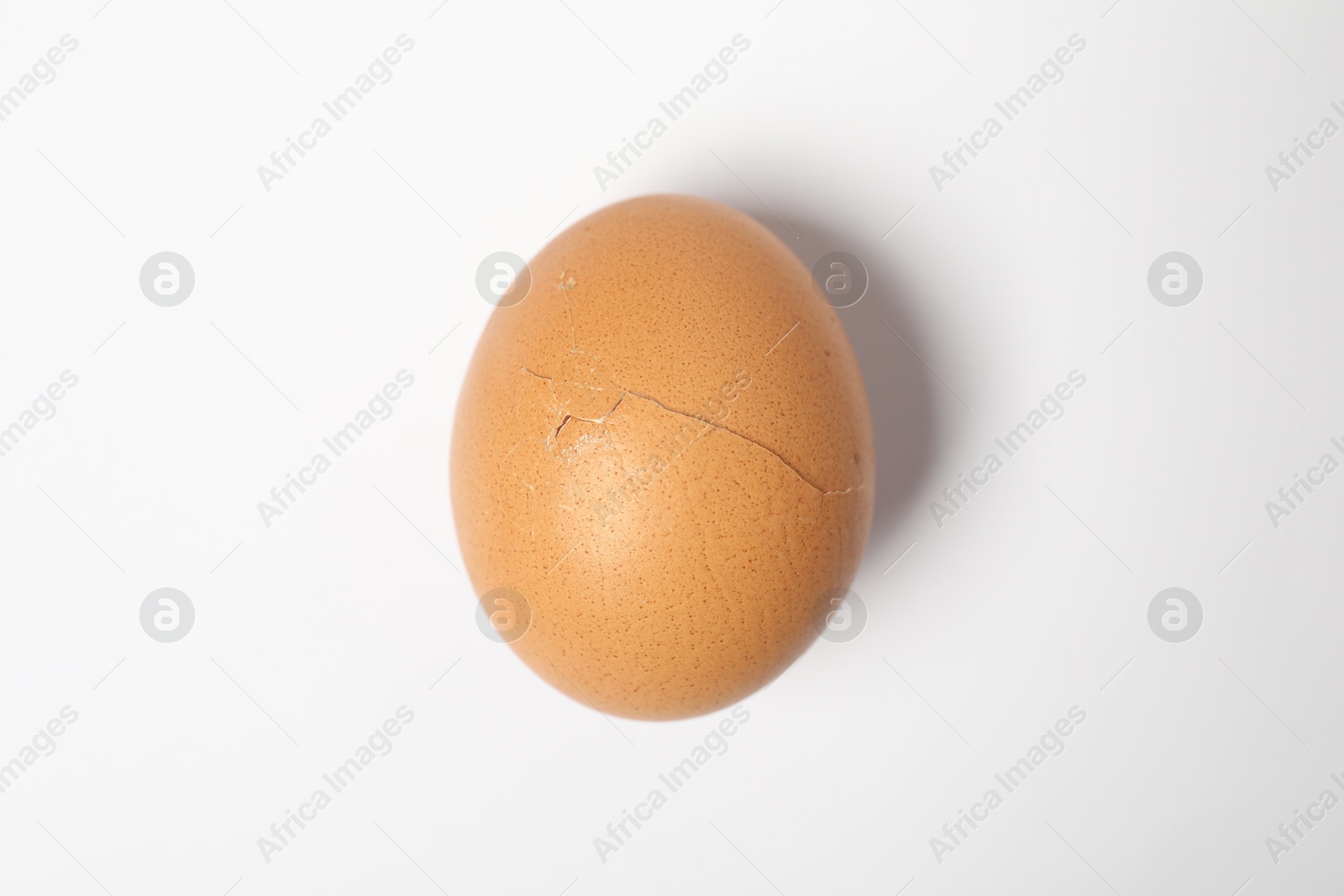 Photo of One egg with cracked shell on white background, top view