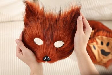 Photo of Quadrobics. Woman with furry fox mask near sofa, closeup