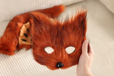 Quadrobics. Woman with furry fox mask near sofa, closeup