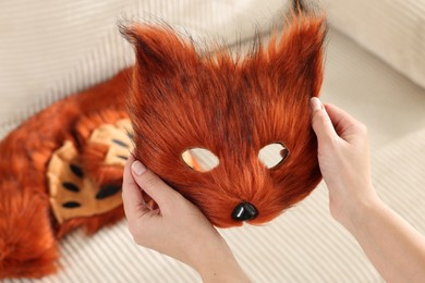 Quadrobics. Woman with furry fox mask near sofa, closeup