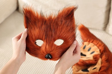 Photo of Quadrobics. Woman with furry fox mask near sofa, closeup