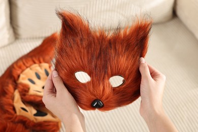 Photo of Quadrobics. Woman with furry fox mask near sofa, closeup