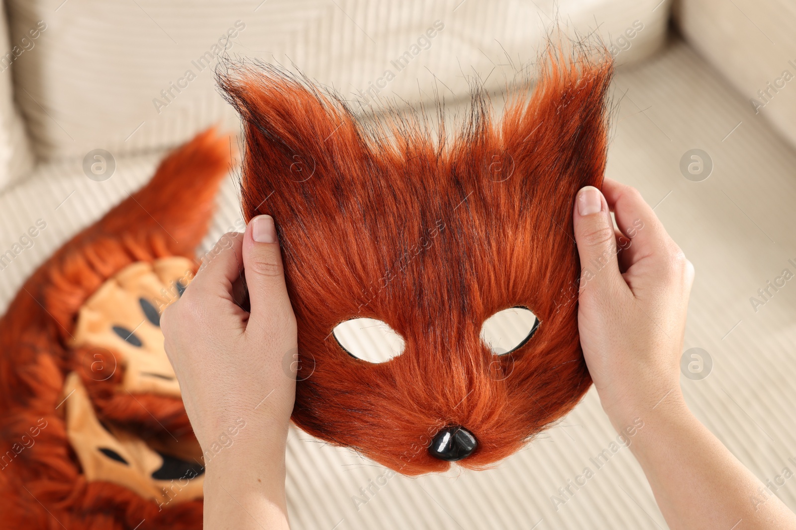 Photo of Quadrobics. Woman with furry fox mask near sofa, closeup