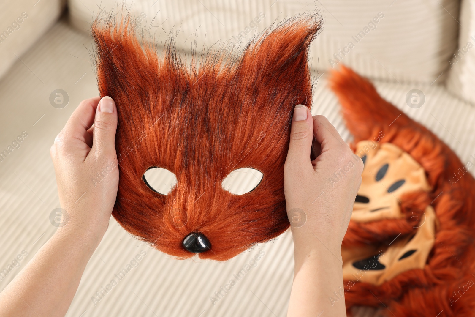 Photo of Quadrobics. Woman with furry fox mask near sofa, closeup