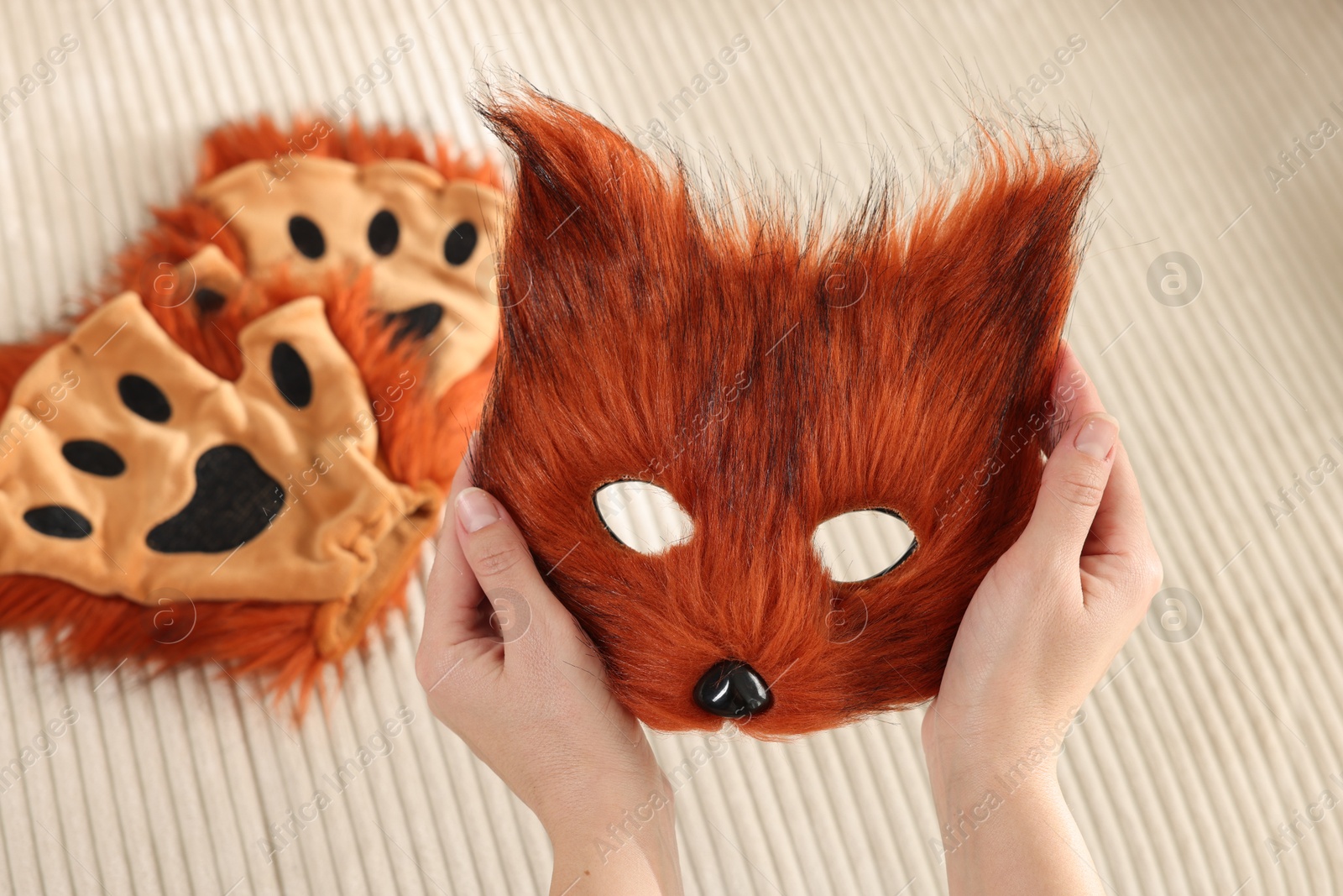 Photo of Quadrobics. Woman holding furry fox mask near sofa with gloves, closeup