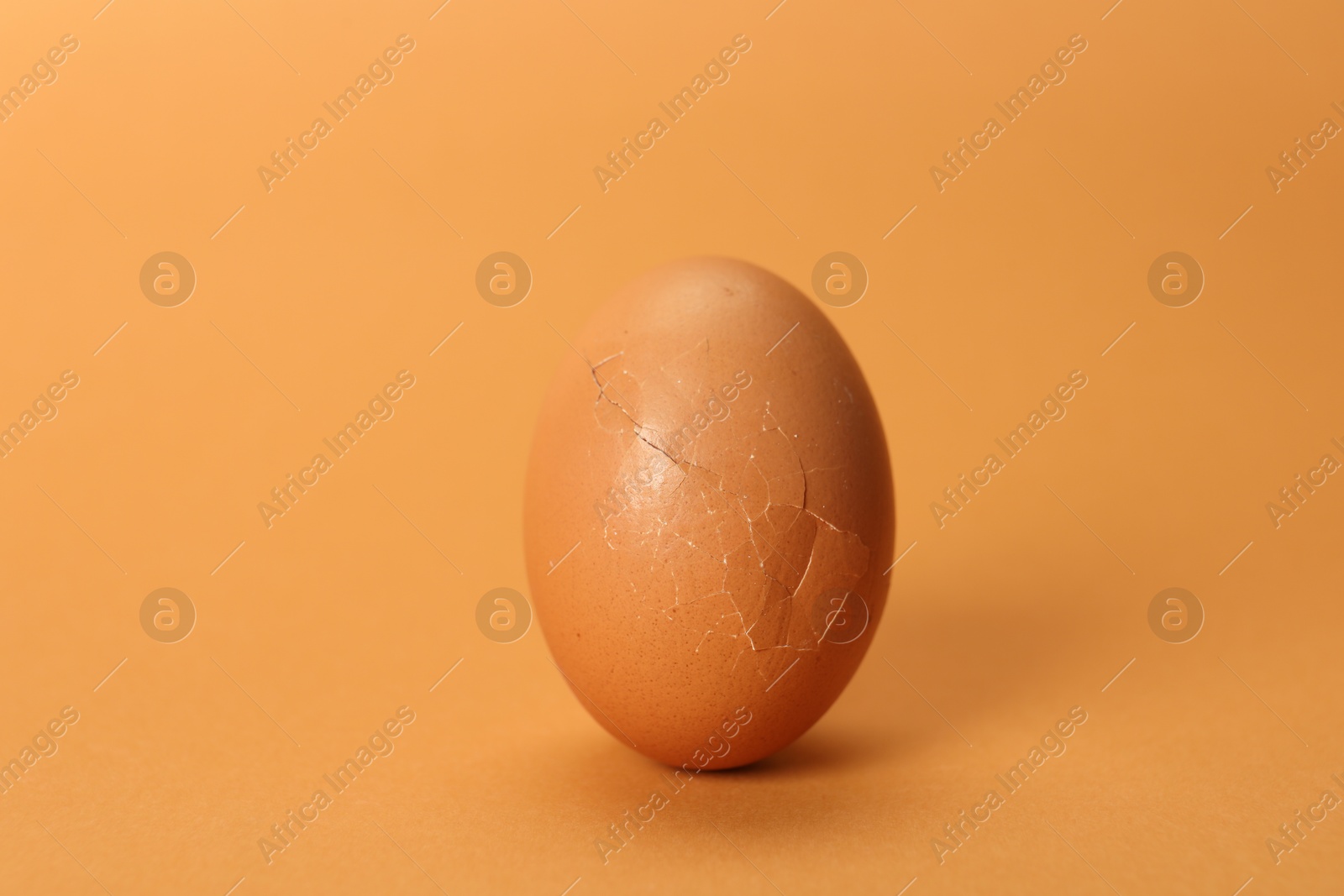 Photo of One egg with cracked shell on coral background, closeup