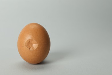 One egg with cracked shell on grey background, closeup. Space for text