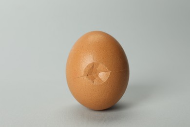 Photo of One egg with cracked shell on grey background, closeup