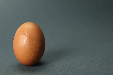 One egg with cracked shell on grey background, closeup. Space for text