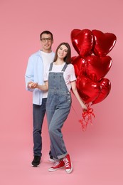 Photo of Lovely couple with heart shaped balloons on pink background. Valentine's day celebration