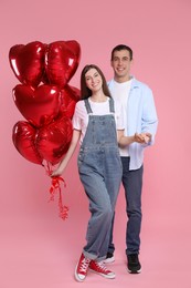 Photo of Lovely couple with heart shaped balloons on pink background. Valentine's day celebration