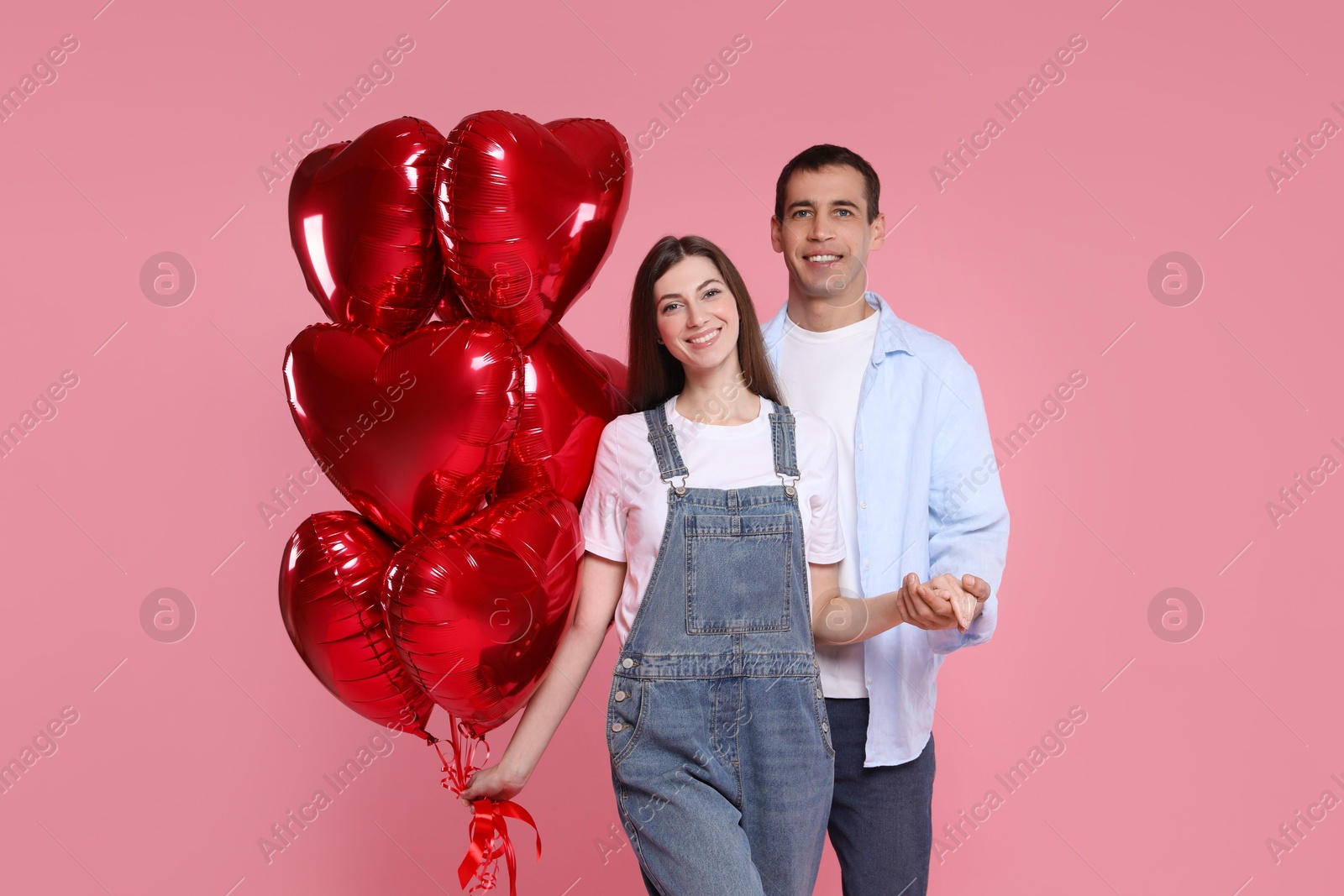 Photo of Lovely couple with heart shaped balloons on pink background. Valentine's day celebration