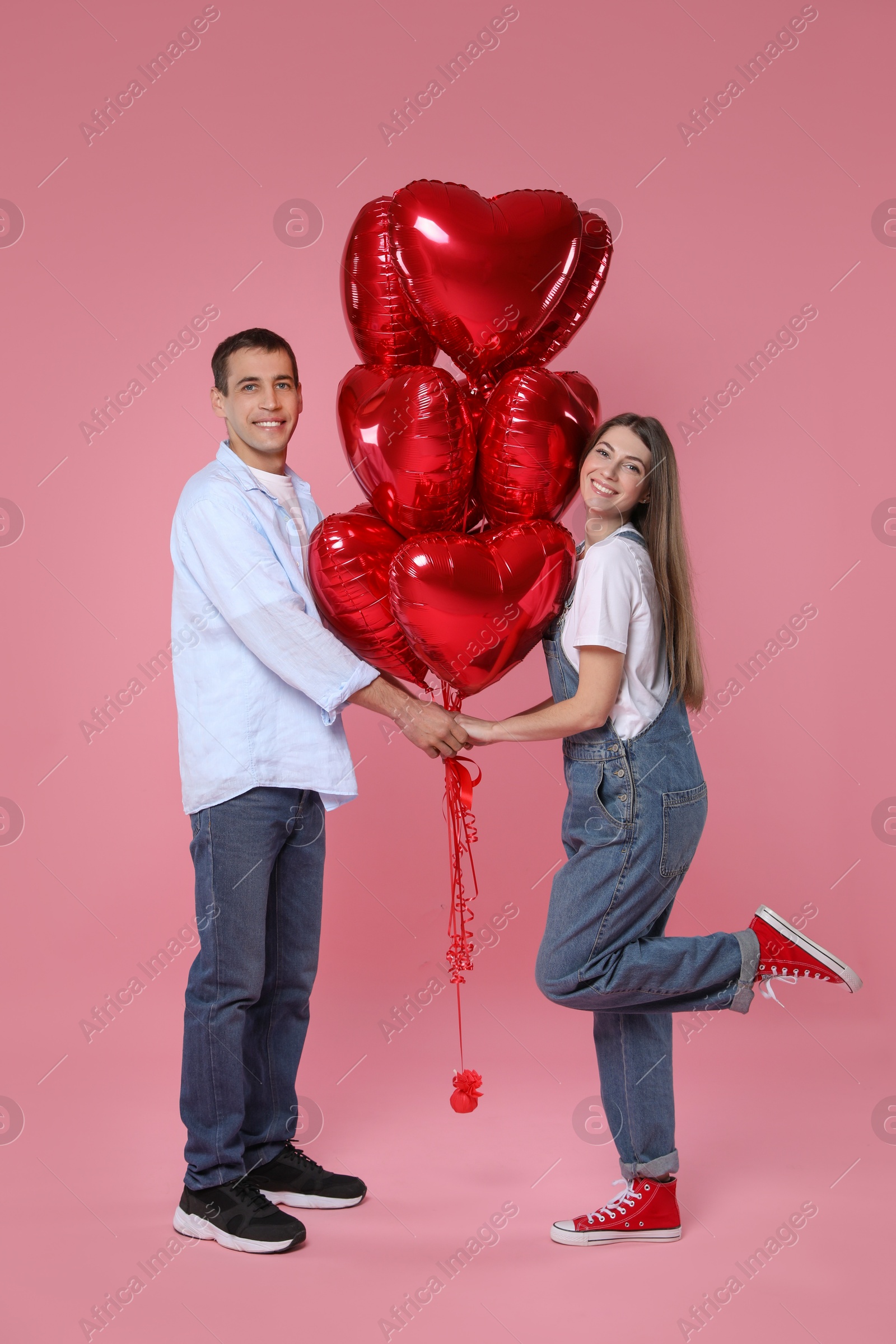 Photo of Lovely couple with heart shaped balloons on pink background. Valentine's day celebration