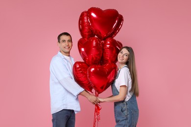 Photo of Lovely couple with heart shaped balloons on pink background. Valentine's day celebration