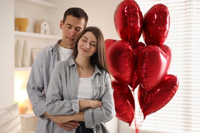 Photo of Lovely couple near heart shaped balloons indoors. Valentine's day celebration