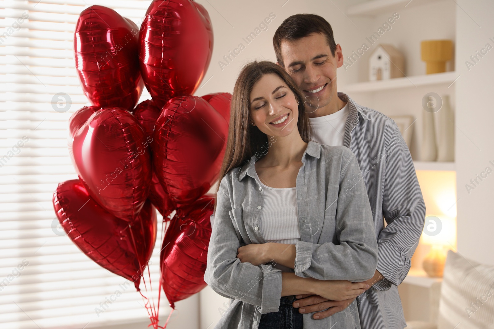 Photo of Lovely couple near heart shaped balloons indoors. Valentine's day celebration