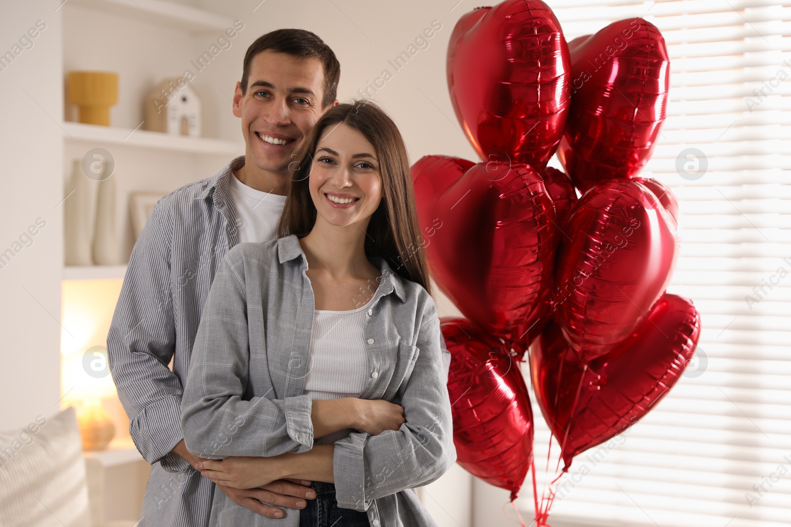 Photo of Lovely couple near heart shaped balloons indoors. Valentine's day celebration