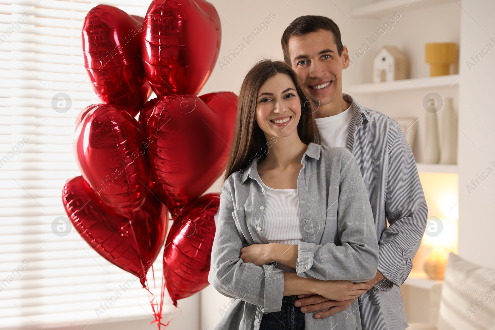 Photo of Lovely couple near heart shaped balloons indoors. Valentine's day celebration