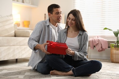 Photo of Lovely couple with gift box indoors. Valentine's day celebration