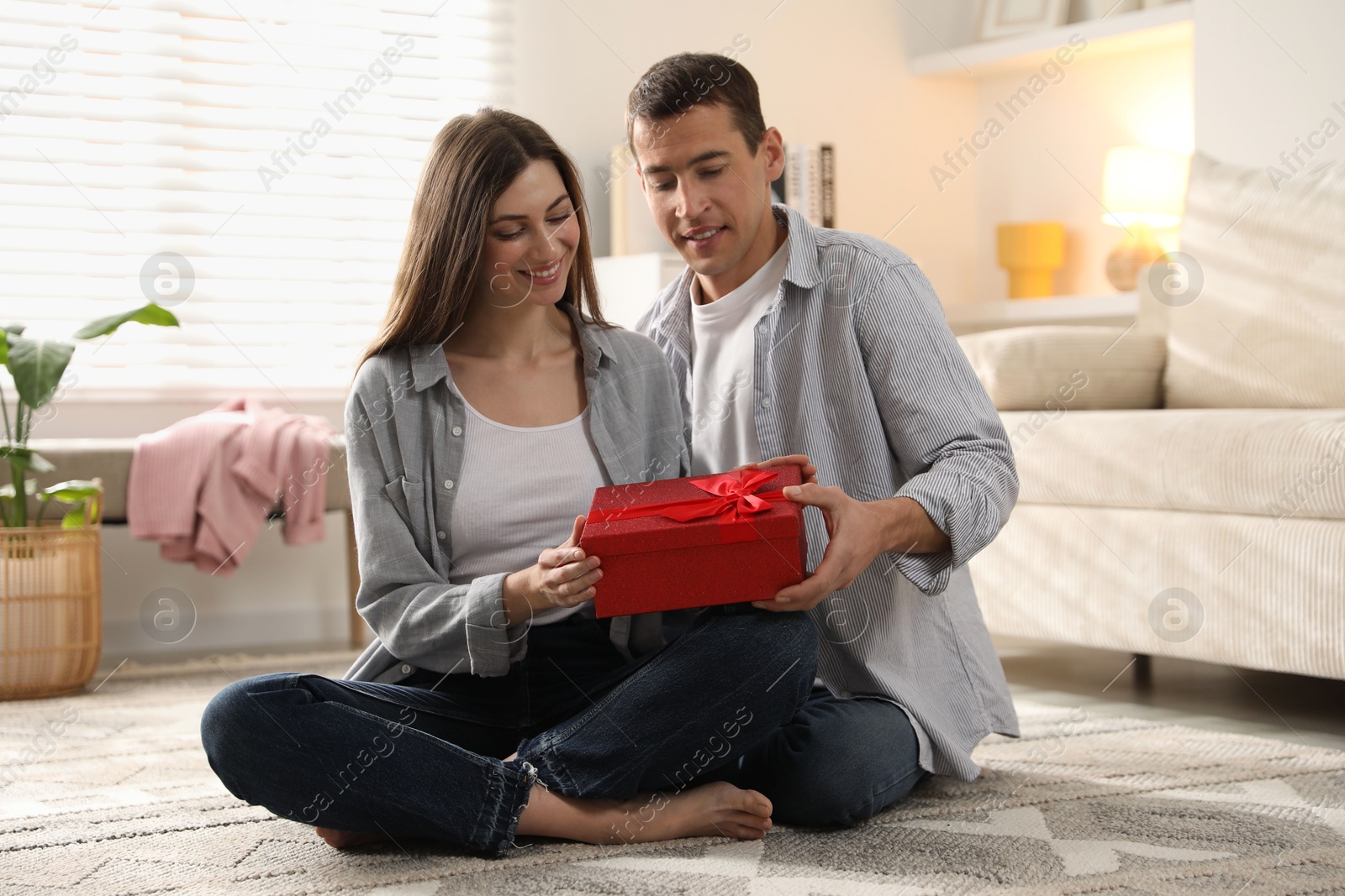 Photo of Lovely couple with gift box indoors. Valentine's day celebration