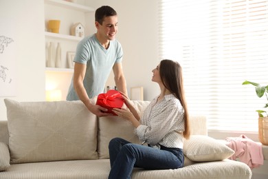 Photo of Lovely man surprising his girlfriend with Valentine's day gift indoors