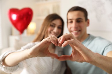 Lovely couple making heart with hands indoors, selective focus. Valentine's day celebration