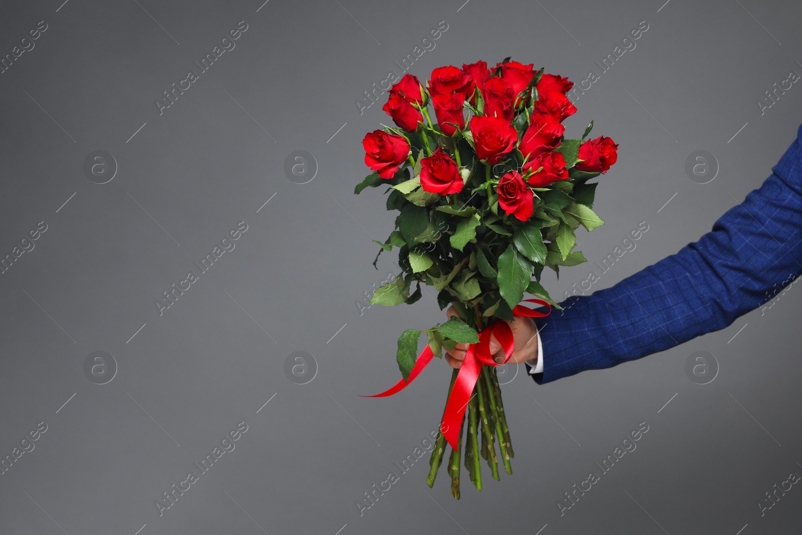 Photo of Happy Valentine's Day. Man with bouquet of roses on grey background, closeup. Space for text