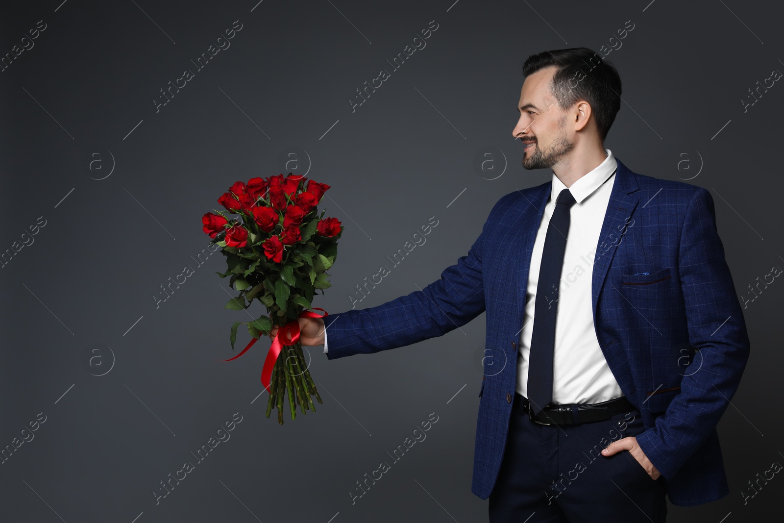 Photo of Happy Valentine's Day. Handsome man with bouquet of roses on grey background