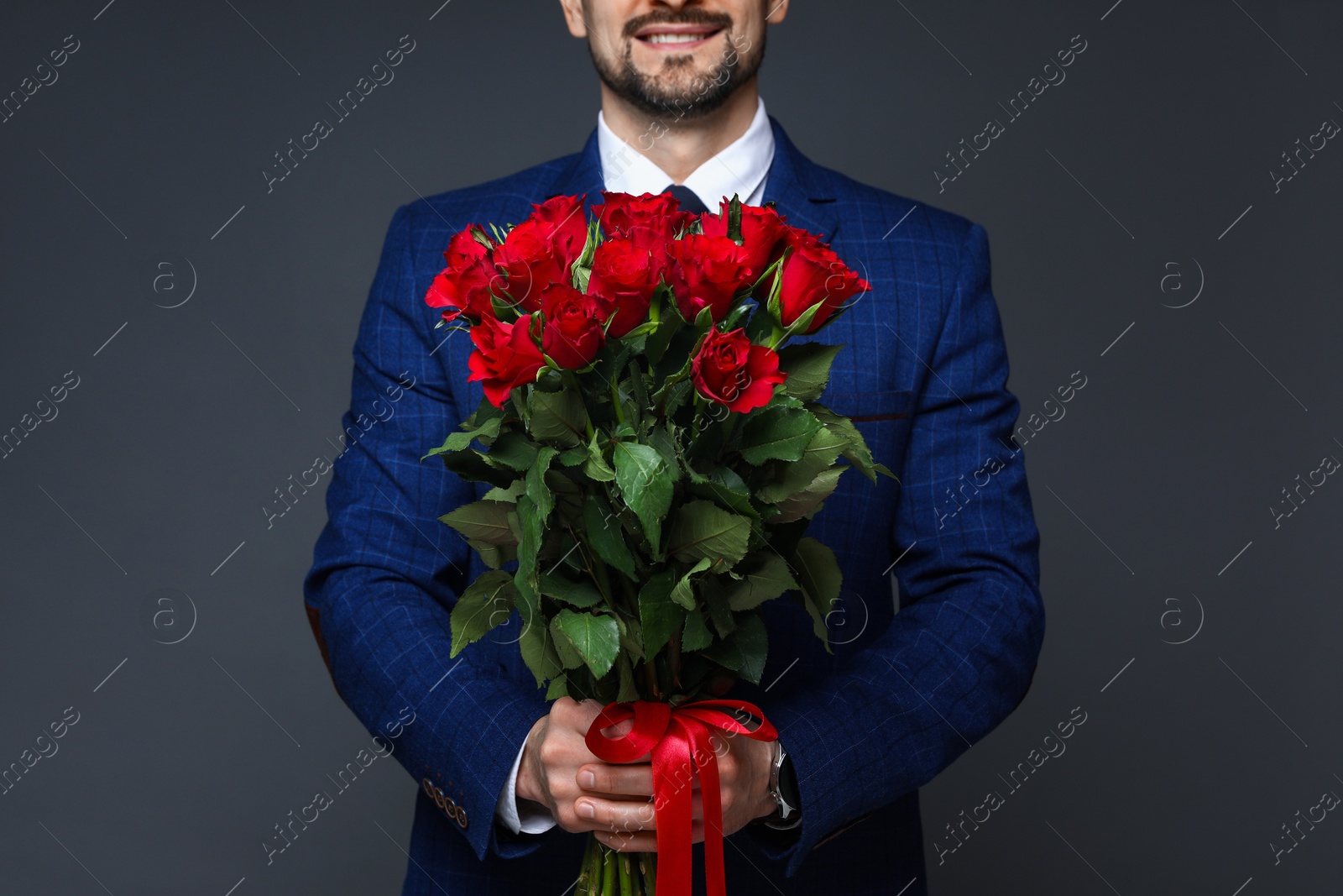 Photo of Happy Valentine's Day. Man with bouquet of roses on grey background, closeup