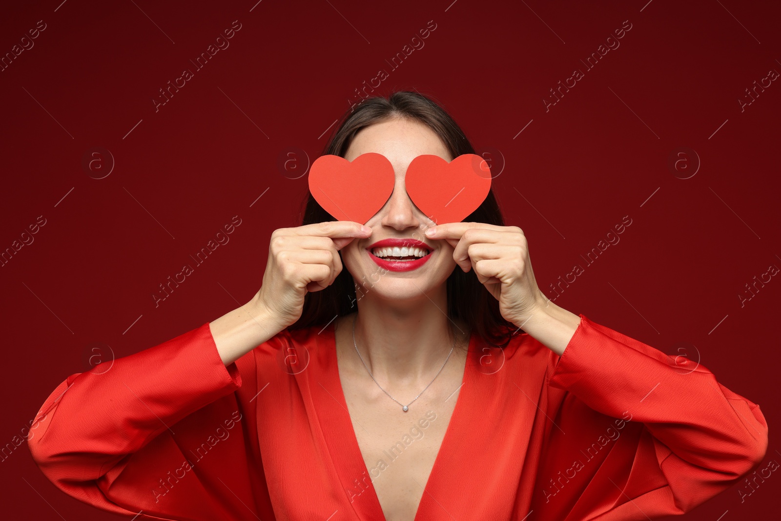 Photo of Happy Valentine's Day. Woman covering her face with paper hearts on red background