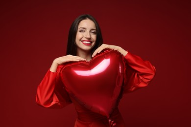 Photo of Happy Valentine's Day. Beautiful woman with heart shaped balloon on red background