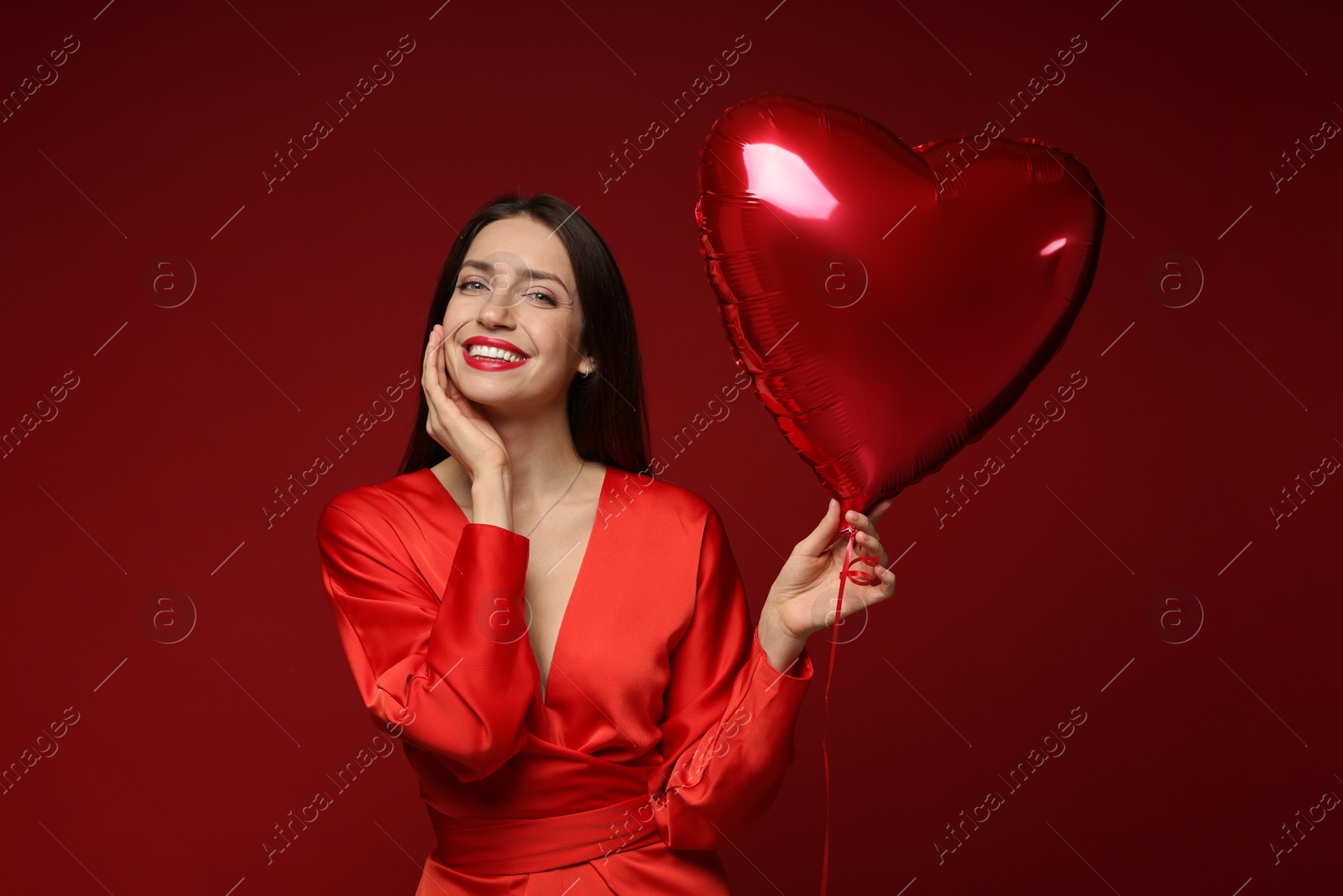 Photo of Happy Valentine's Day. Beautiful woman with heart shaped balloon on red background