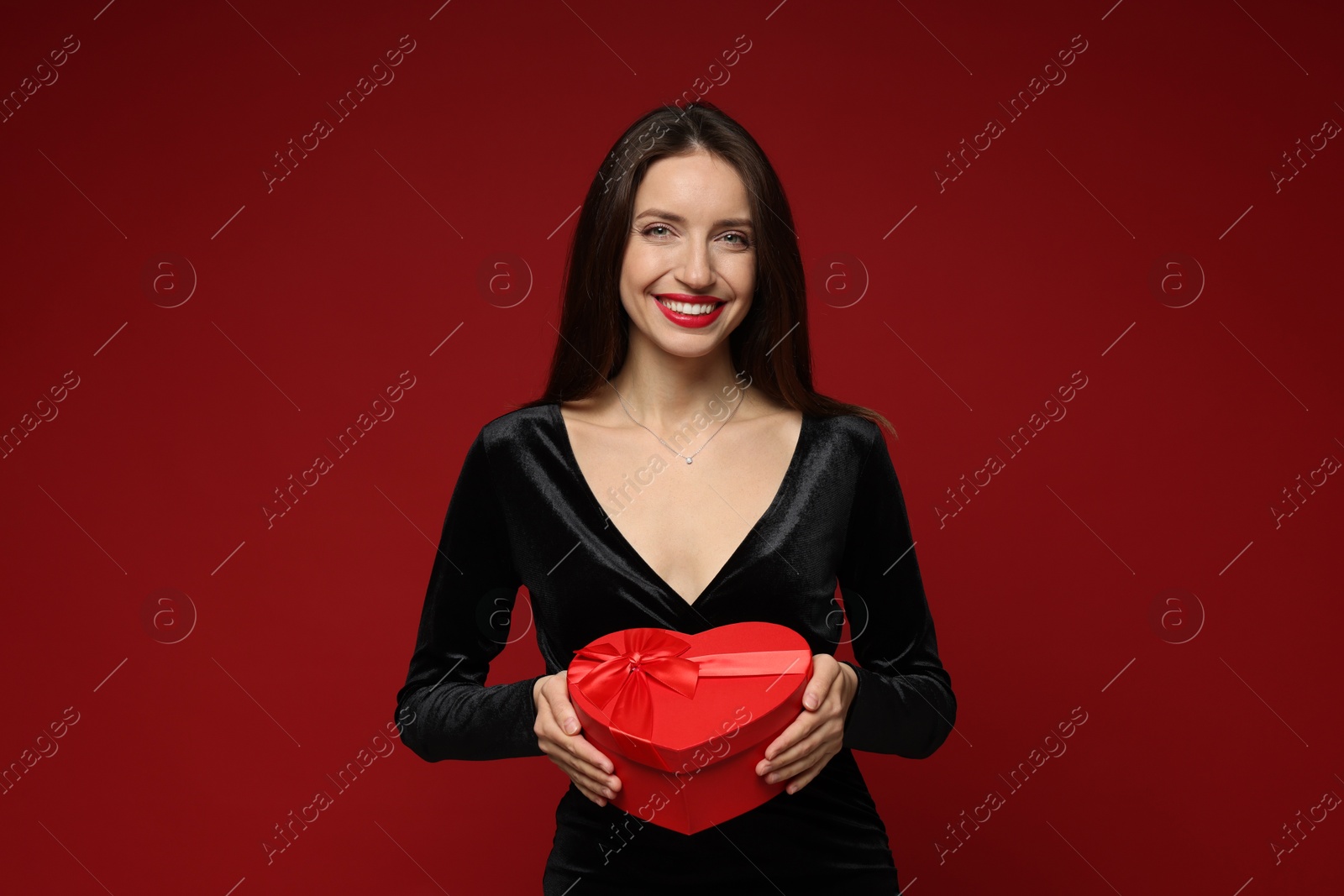 Photo of Happy Valentine's Day. Beautiful woman with heart shaped gift box on red background