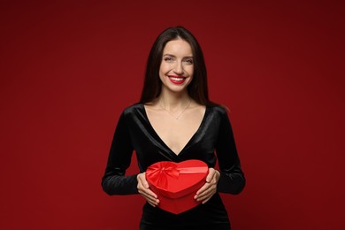 Photo of Happy Valentine's Day. Beautiful woman with heart shaped gift box on red background