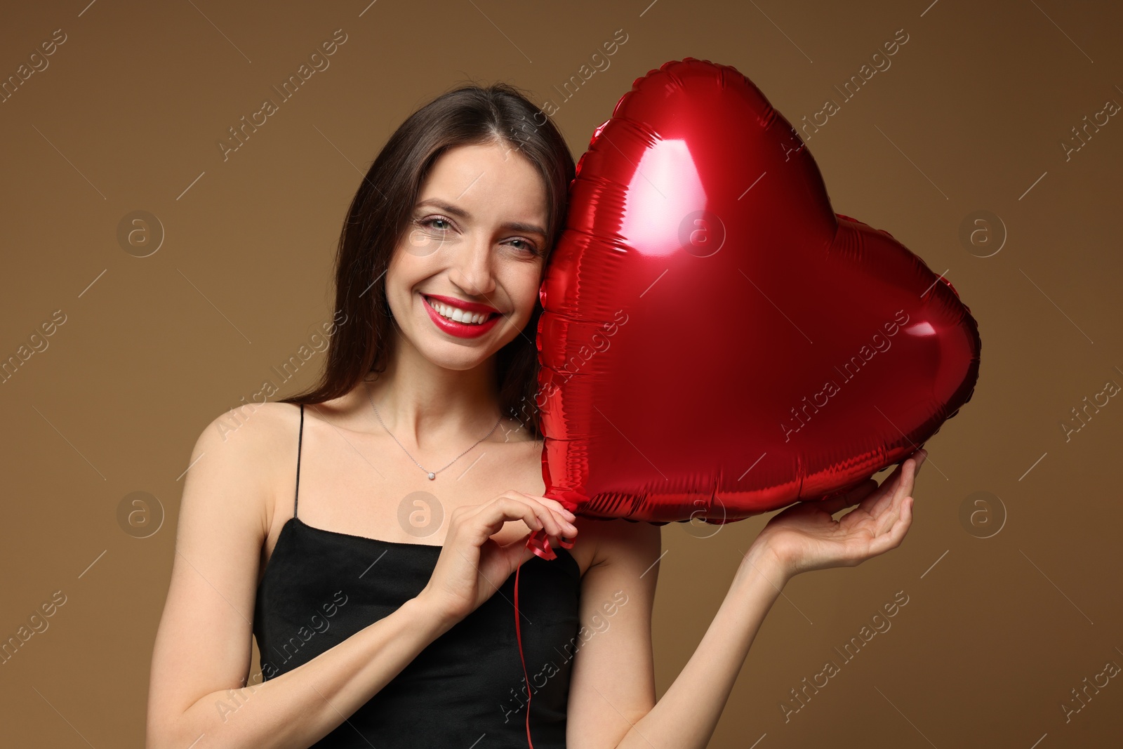 Photo of Happy Valentine's Day. Beautiful woman with heart shaped balloon on brown background