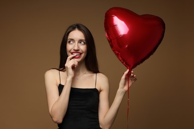 Photo of Happy Valentine's Day. Beautiful woman with heart shaped balloon on brown background