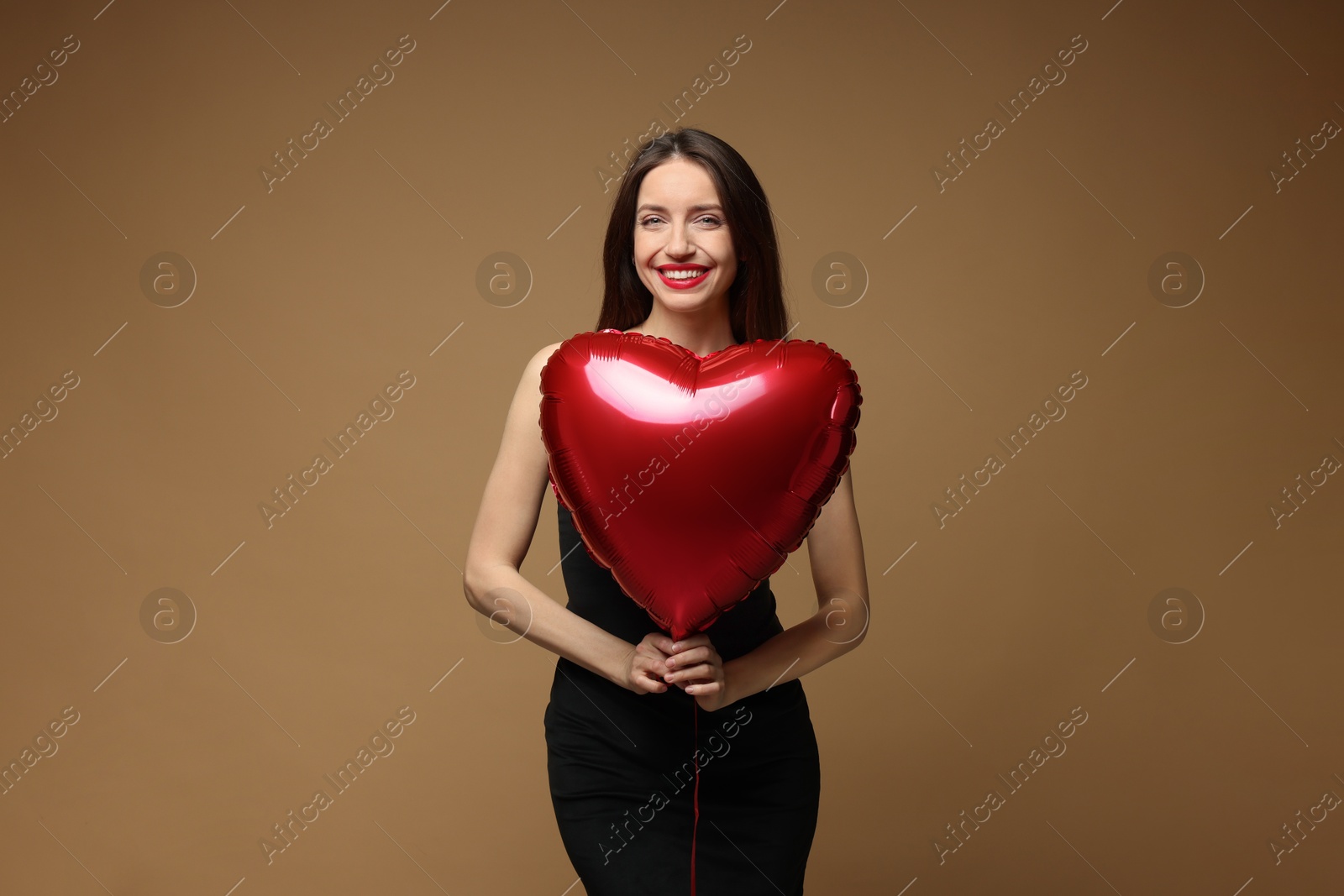 Photo of Happy Valentine's Day. Beautiful woman with heart shaped balloon on brown background