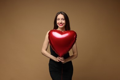 Photo of Happy Valentine's Day. Beautiful woman with heart shaped balloon on brown background